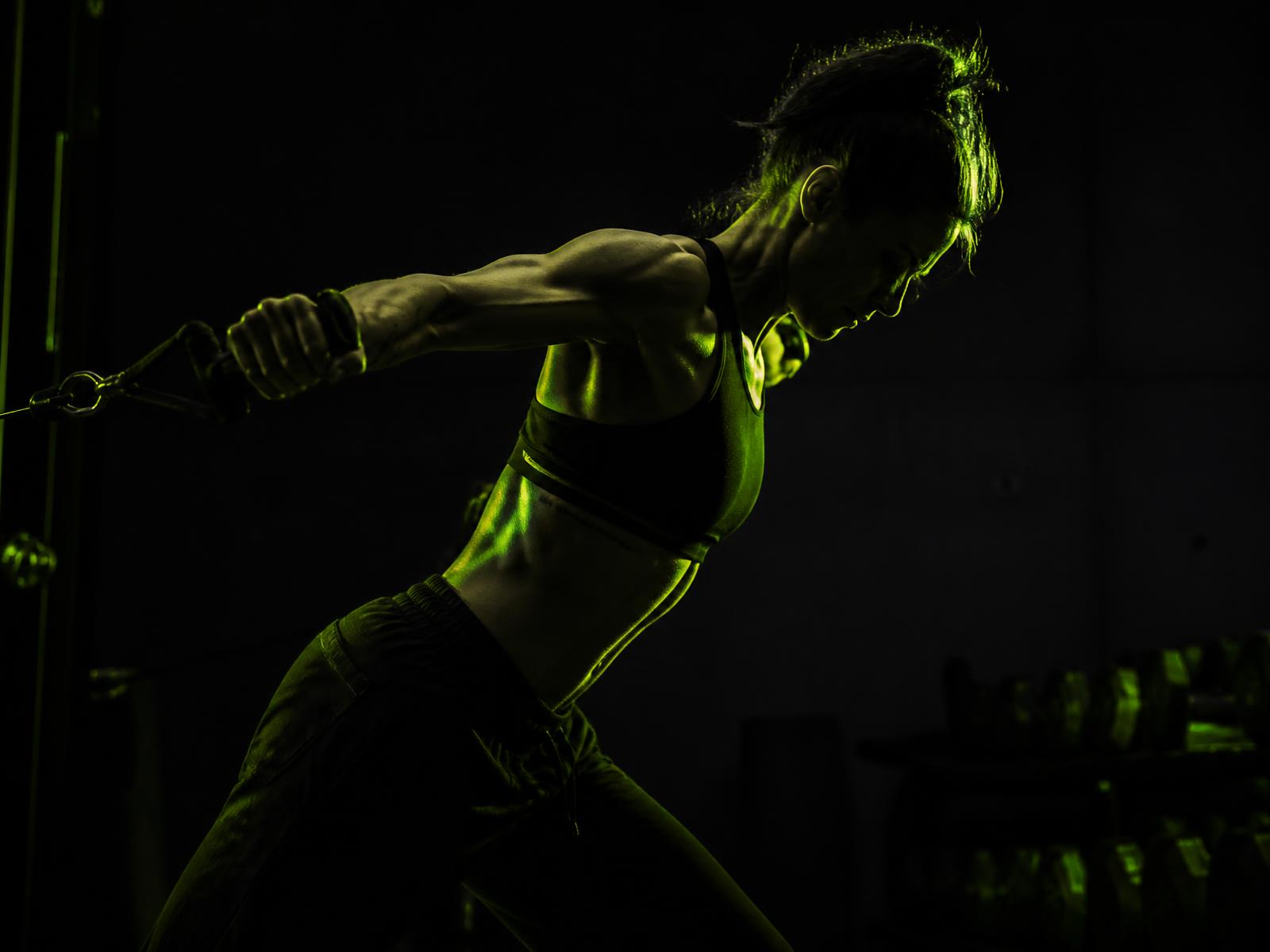 Athlete completing a resistance training set in a dark gym